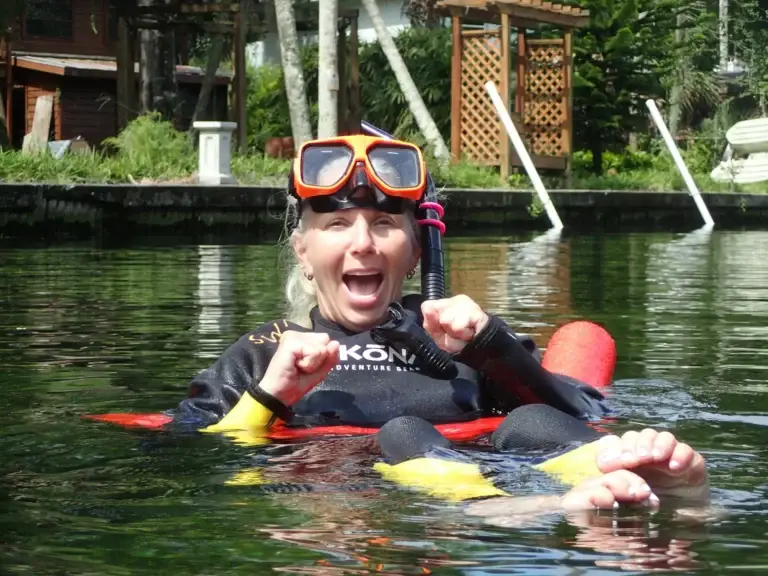 A guest laughing in the water after meeting a manatee