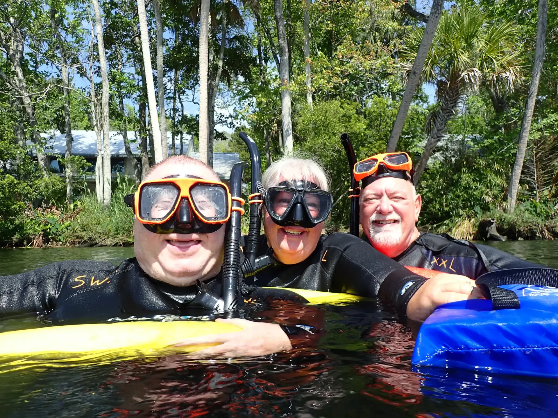 Three guests in snorkel masks grinning in the river