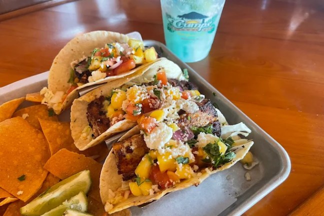 Tray with tacos, lime wedges, chips, and a drink.